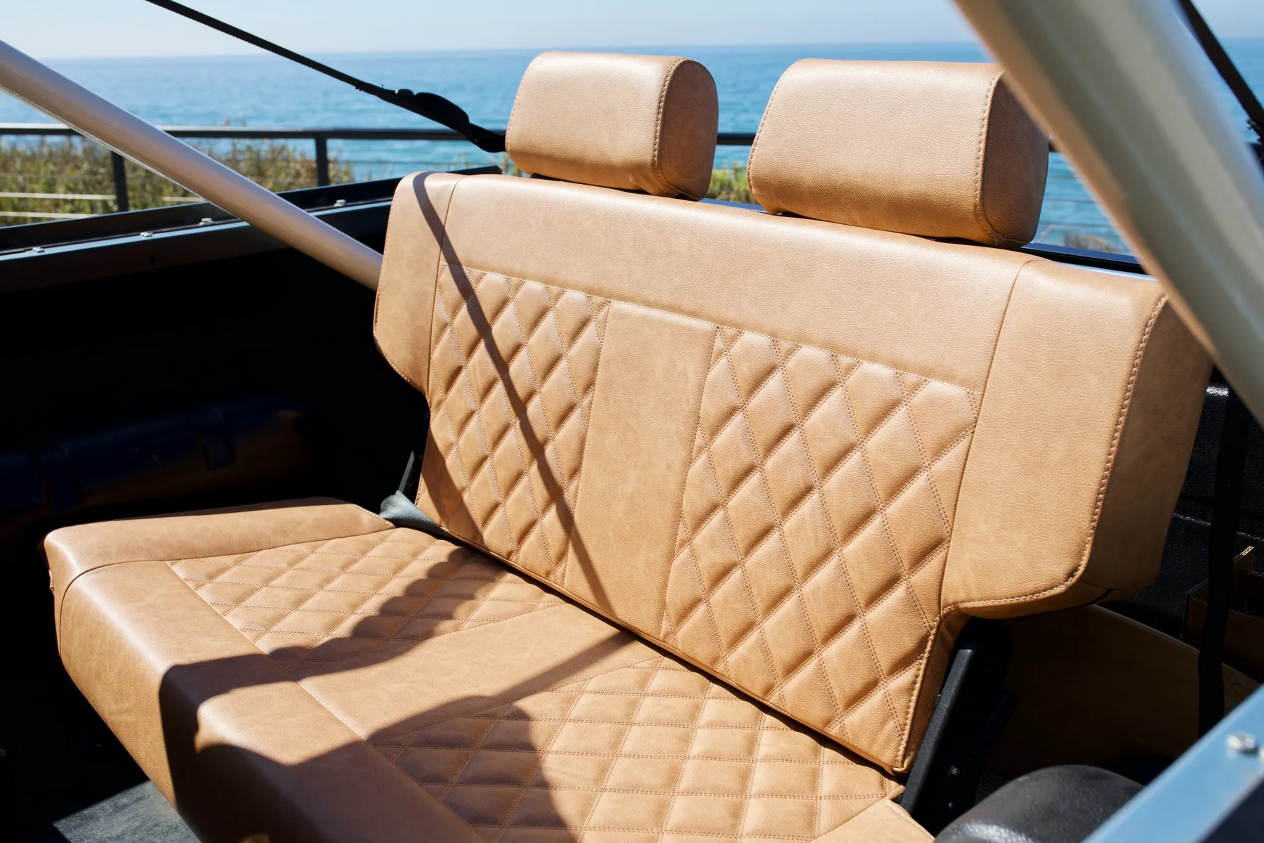 Diamond-stitched tan leather bench seat with the Pacific behind